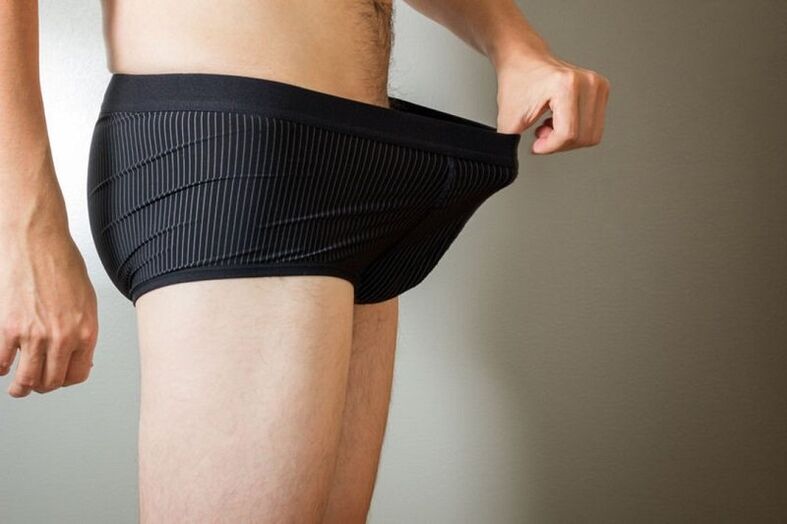 Un homme baisse les yeux sur son pantalon et veut agrandir son pénis avec de la limonade